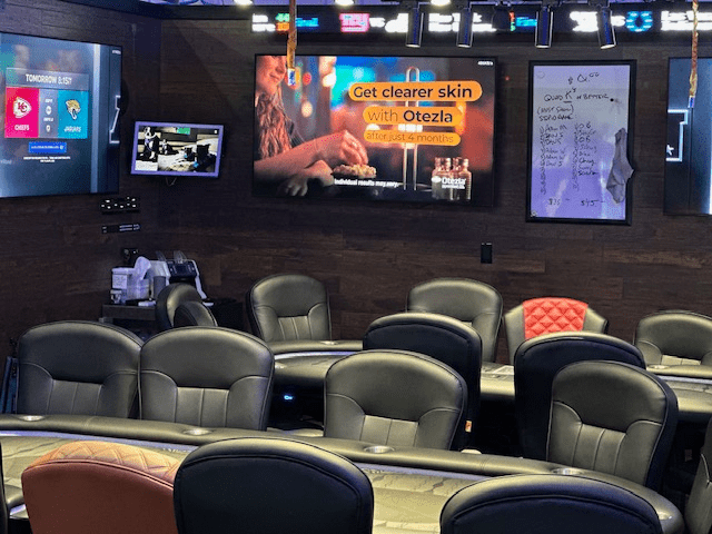 Empty poker room with chairs and TV screens.